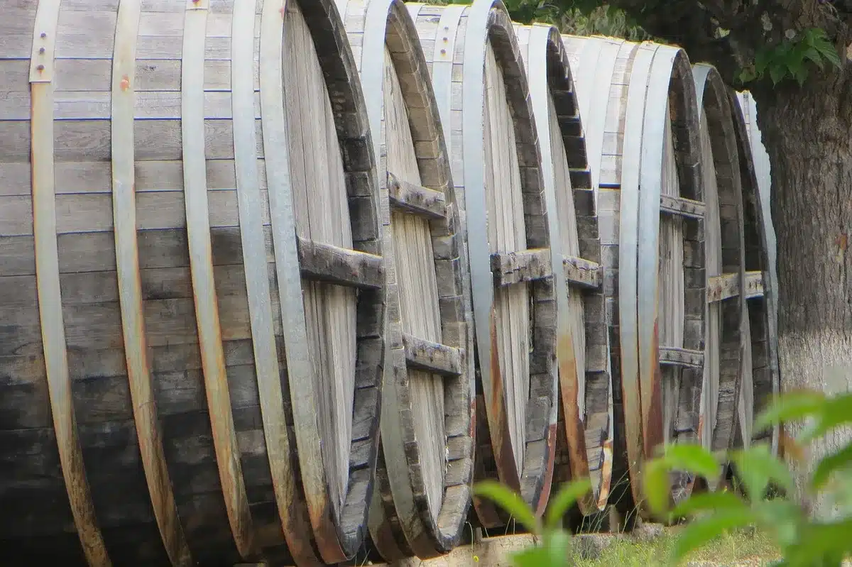 Empty 17th-century streets at dusk with a single lantern-lit cart and stacked wooden barrels suggesting a secret plot
