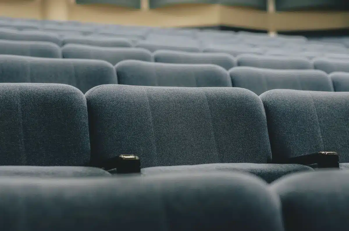 wide empty theatre with a single spotlight on an unbranded vintage microphone, dust motes in the beam, no people