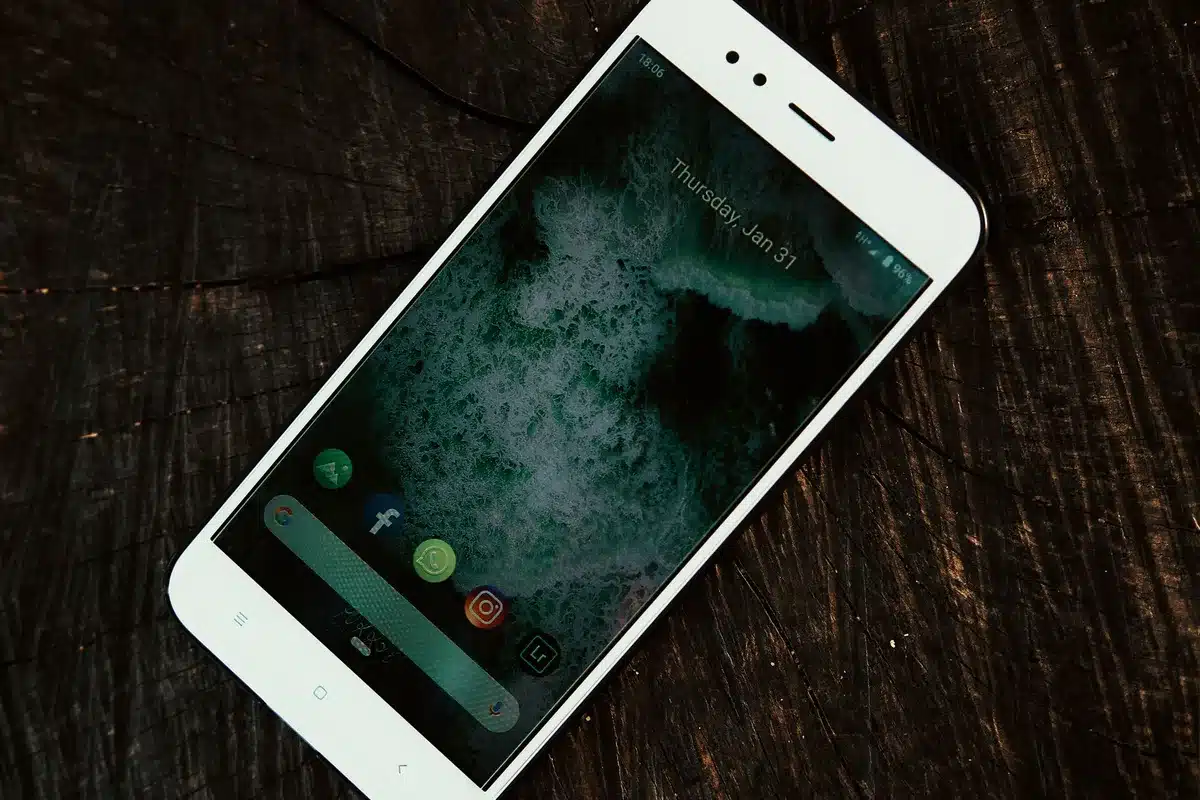Close-up of an unbranded modern smartphone lying on a textured table, screen dark, subtle reflections, a compact device suggesting premium build