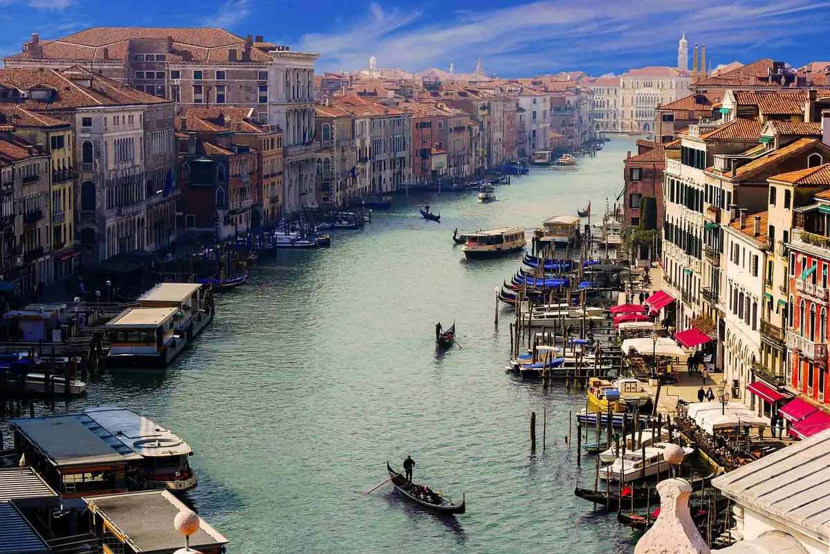 A Venice canal at dusk with an empty gondola and fog rising, muted lights reflecting on water, no people