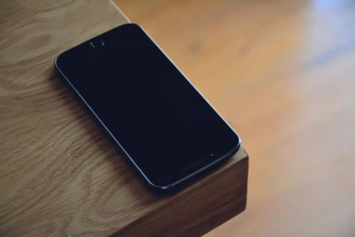 Empty wide studio table with an unbranded smartphone silhouette, a folded cloth beside it and soft overhead light