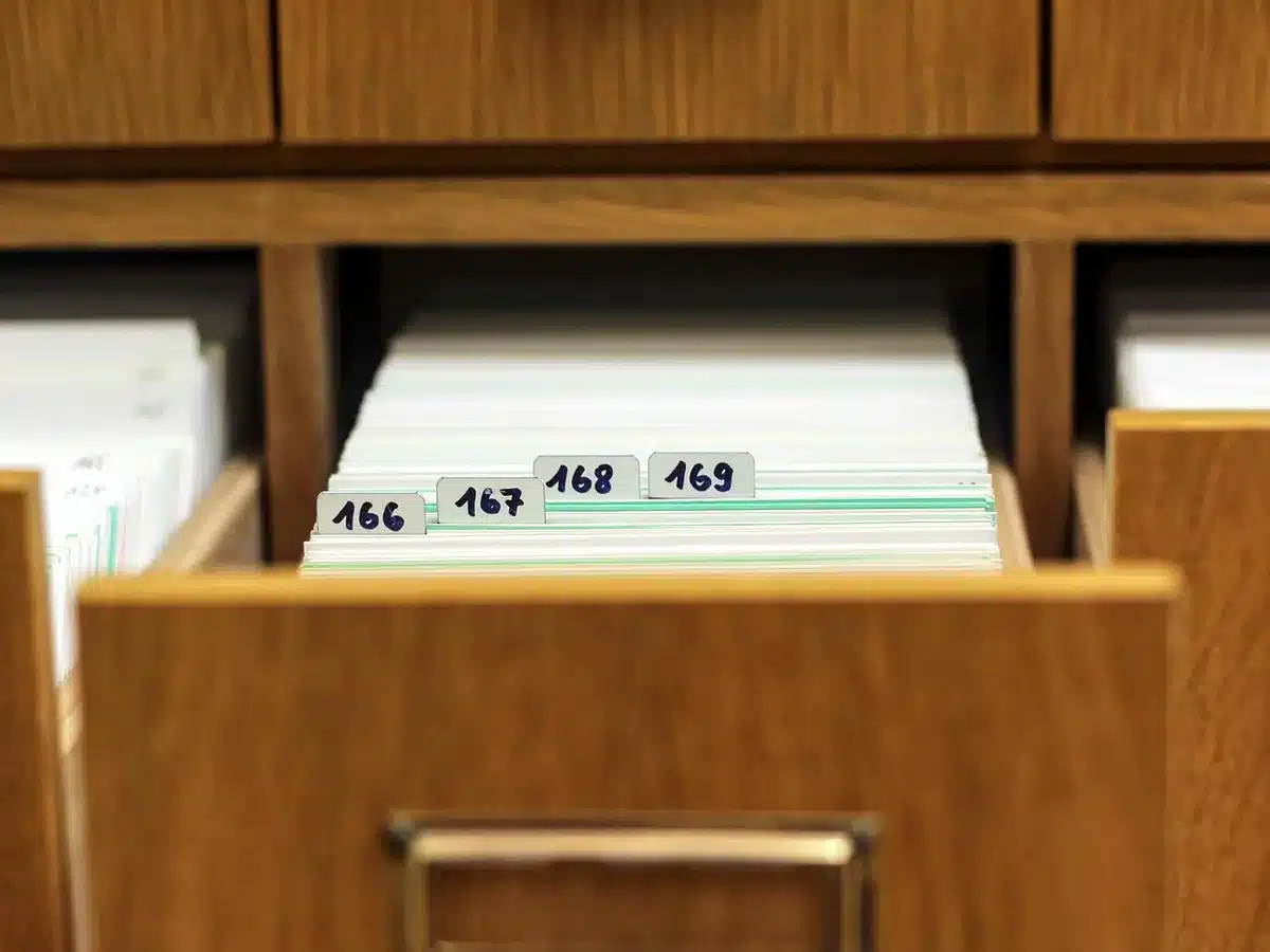Close-up of filing documents on a desk with a magnifying glass and a generic smartphone nearby