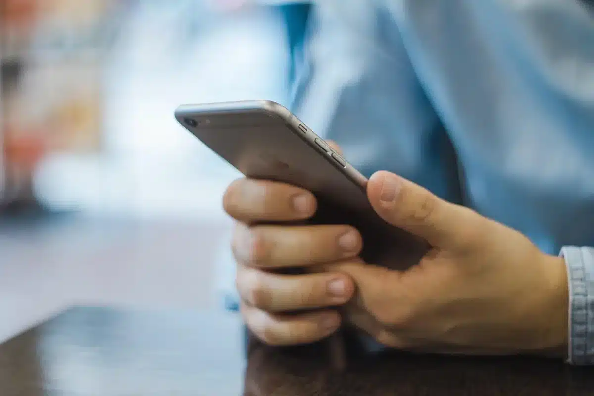 A close-up abstract scene of a generic modern smartphone laying on a table, screen dark but with soft reflections suggesting a high-refresh OLED panel; no logos or text