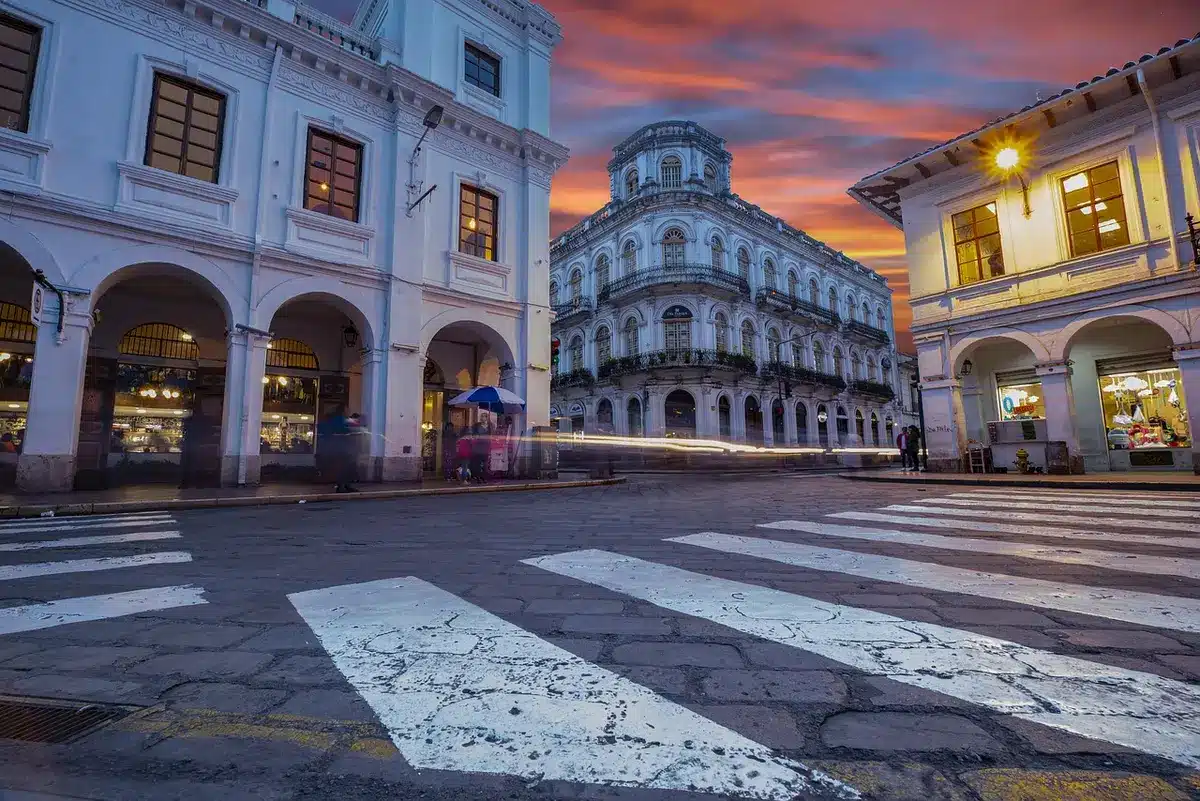 An empty colonial street in Campeche's historic center lined with temporary altar platforms, marigold petals scattered on cobblestones, paper decorations hanging between buildings