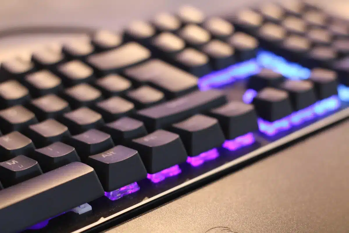empty gaming desk with an anonymous laptop open, colorful RGB keyboard glow, headset resting beside it