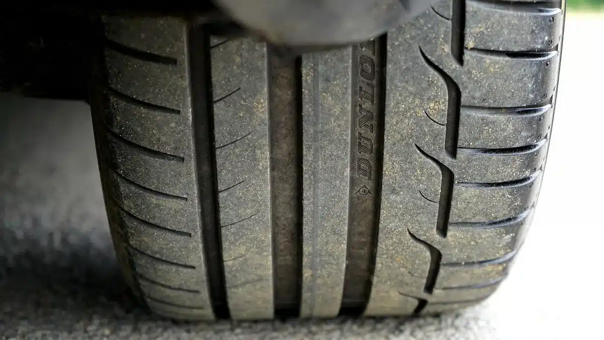 A close-up of an unbranded tire assembly showing a removable outer tread ring being lifted away from the wheel, tools nearby, no logos or people
