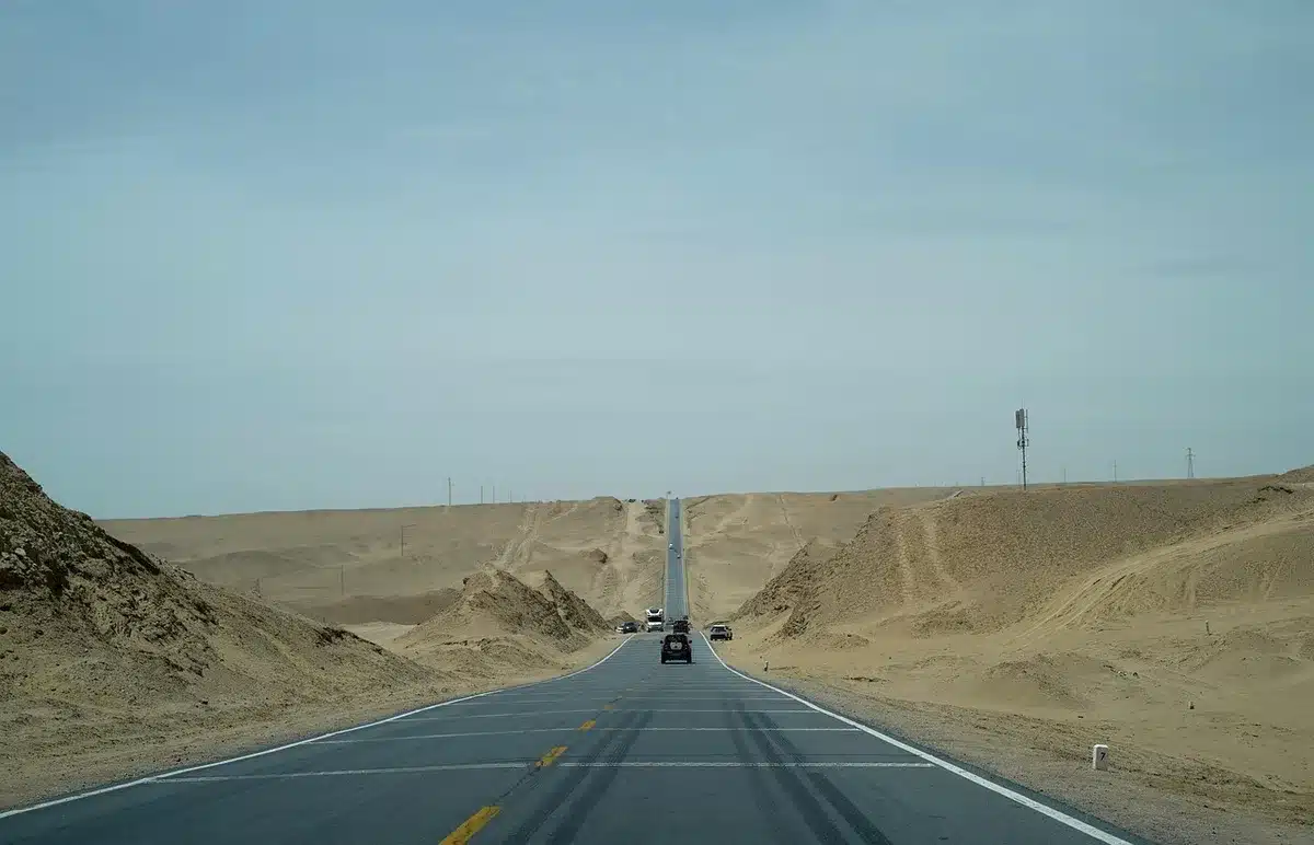 Empty stretch of rural highway under construction, stacked earthworks and distant machinery