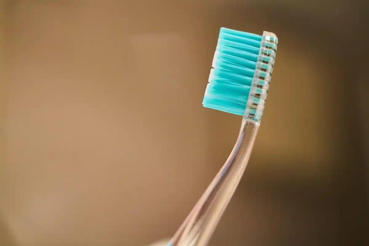 An anonymous bathroom shelf displaying generic oral-care accessories and a small unbranded device box, soft daylight through a frosted window