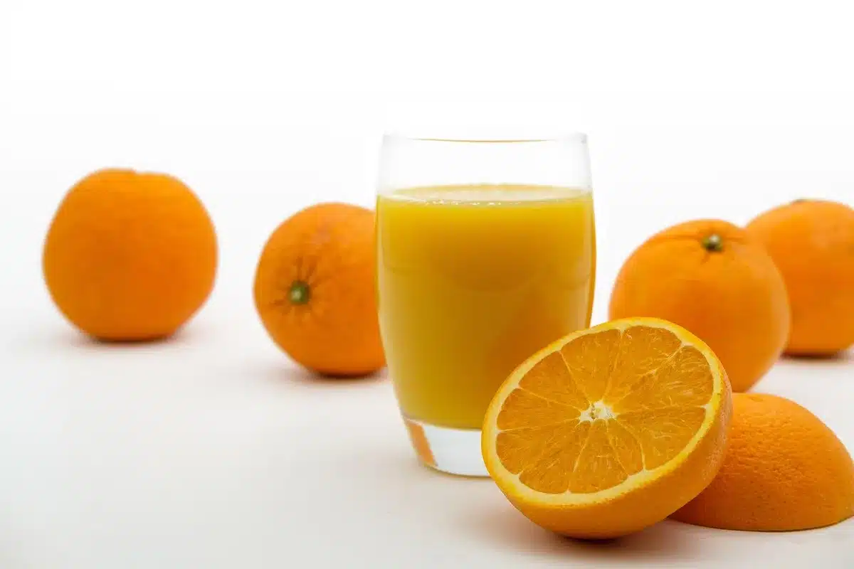 glass of orange juice on a kitchen table, no brand, blurred morning window in background