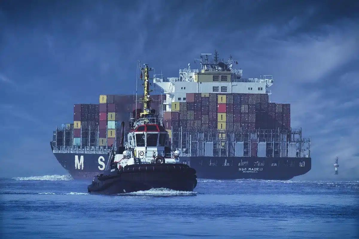 Exterior of a generic modern warehouse at dusk with shipping containers stacked outside and anonymous workers moving crates, no logos or faces visible
