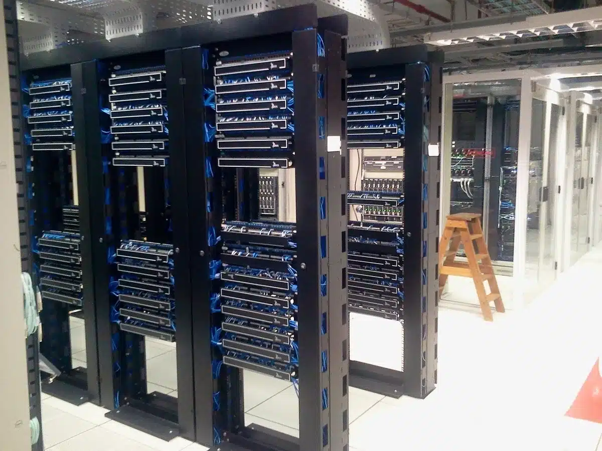 Empty modern server room aisle with glowing rack lights, no people, cables and racks stretching into depth