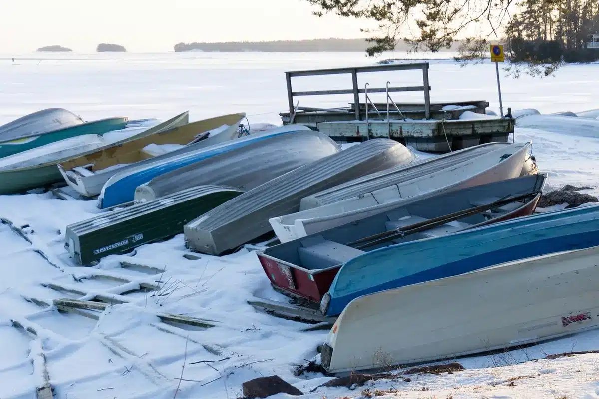 empty coastal road with small boats pulled onto pavement, anonymous figures securing ropes