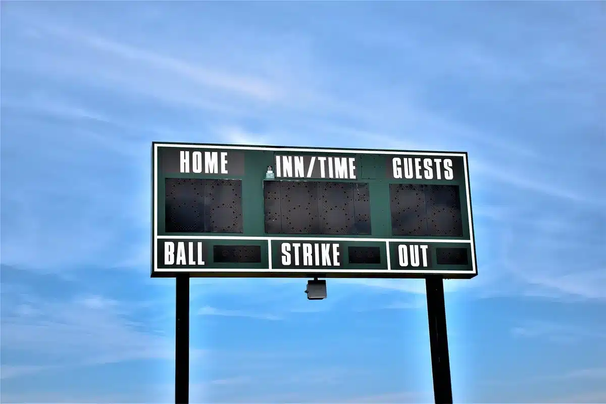 close-up of an unbranded scoreboard and an anonymous clipboard with lineup sheets on bench