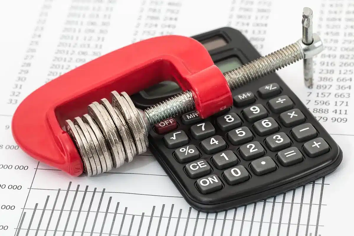 Manos sosteniendo papeles de presupuesto y una calculadora sobre un escritorio
