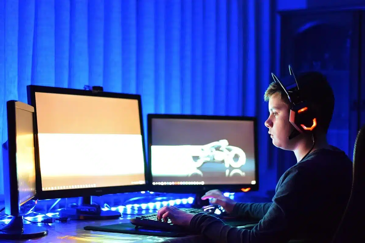 low-profile black gaming keyboard on empty desk with detachable wrist rest, RGB glow reflected on surface