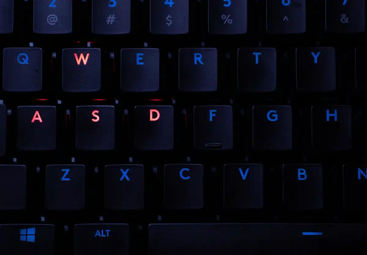 close-up of RGB keyboard edge and wrist rest on dark tabletop, soft colored lights