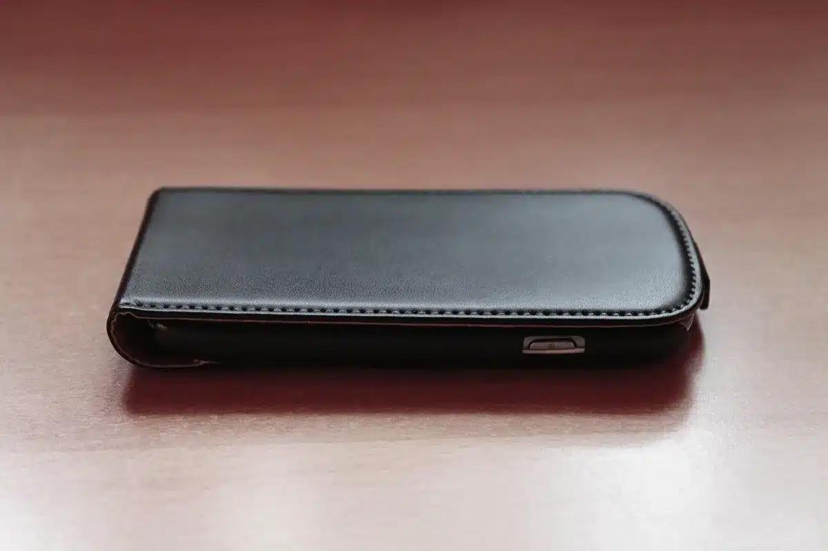 Close-up of a hard Pelican-style protector case open with a foam cutout holding an anonymous handheld device and cable, no branding