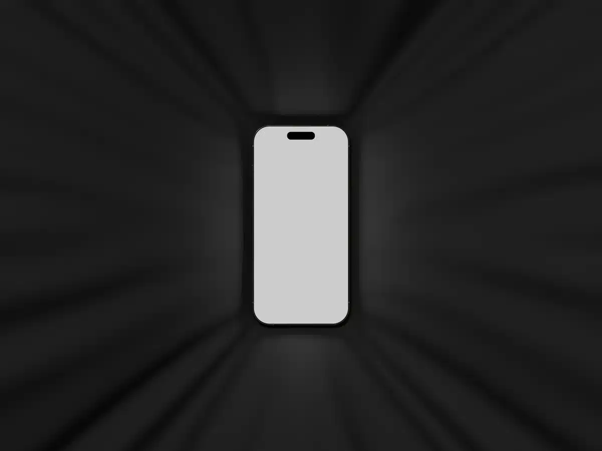 Close-up of an anonymous hand holding a generic mid-range smartphone against a neutral background, screen off, no branding