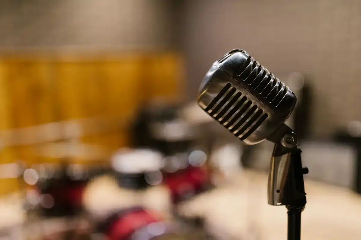 Empty stage with a single vintage microphone under a hard spotlight, dust motes in the beam