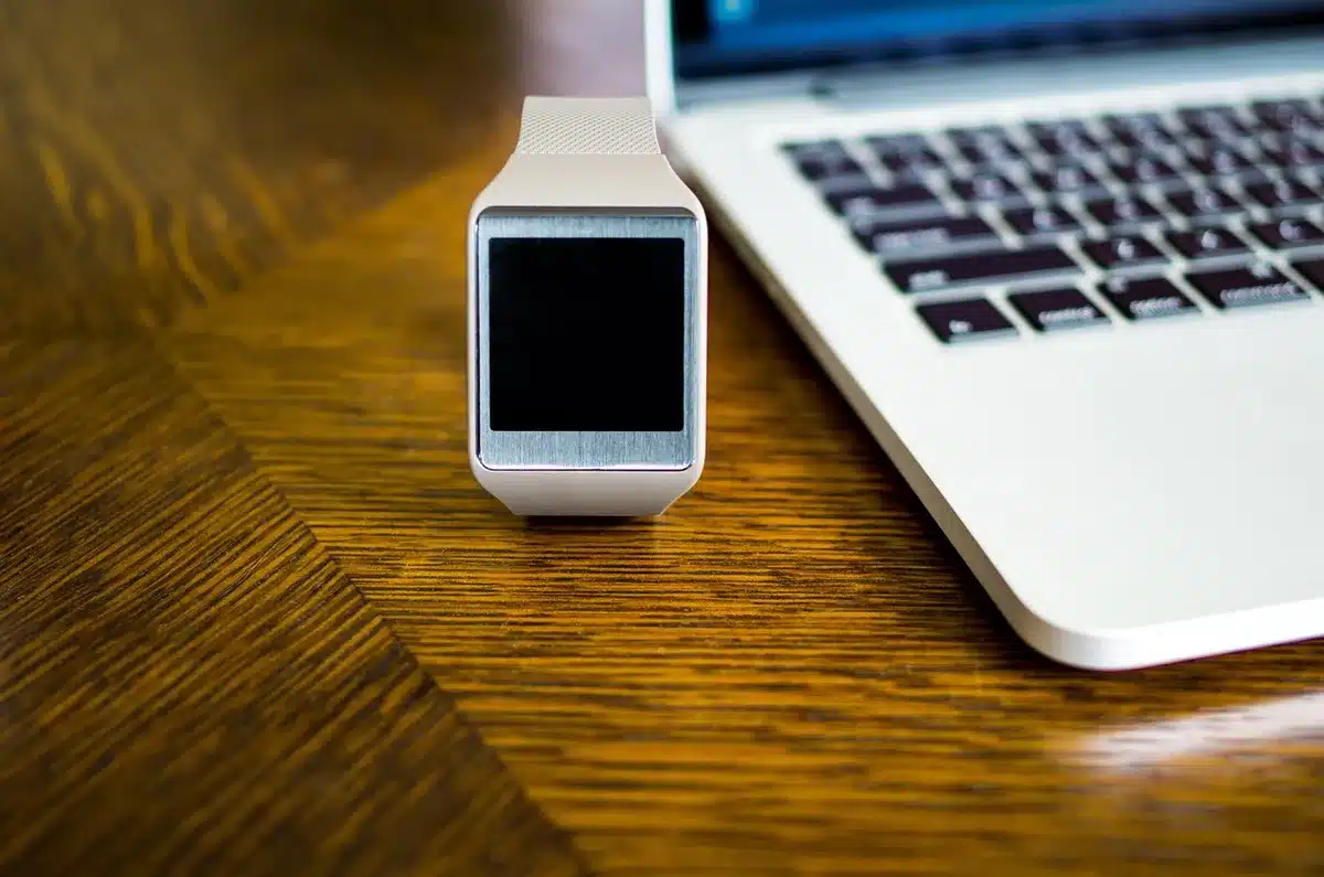 Close-up of an anonymous unbranded smartwatch face resting on a clean tabletop, showing health metrics on screen but no logos