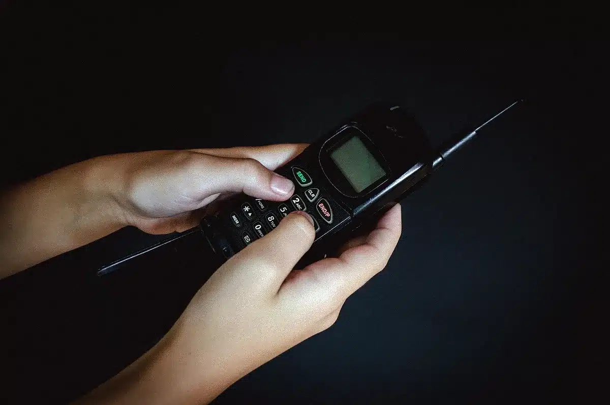 anonymous hand holding phone with an SMS warning screen, background an out-of-focus home table, no identifiable people