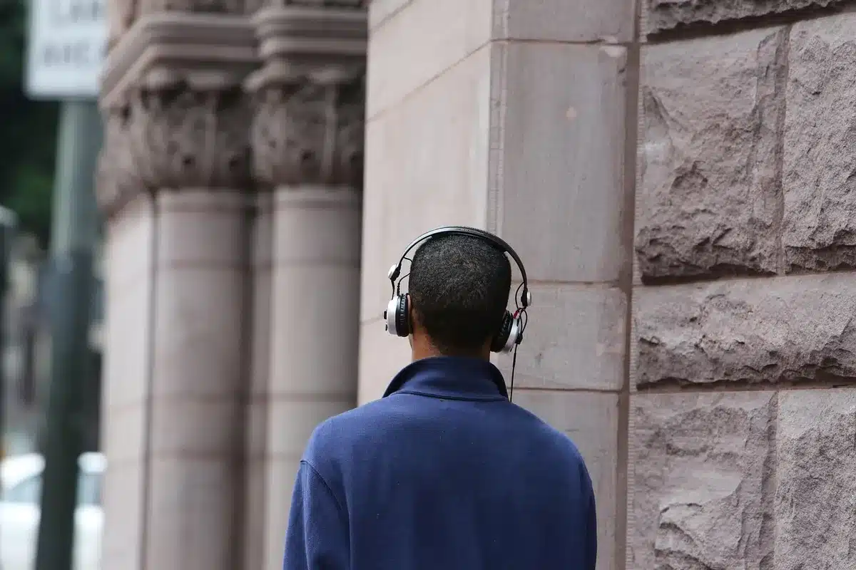 Close-up of unbranded headphone earcup on a wooden table next to a smartphone showing a generic shopping app interface