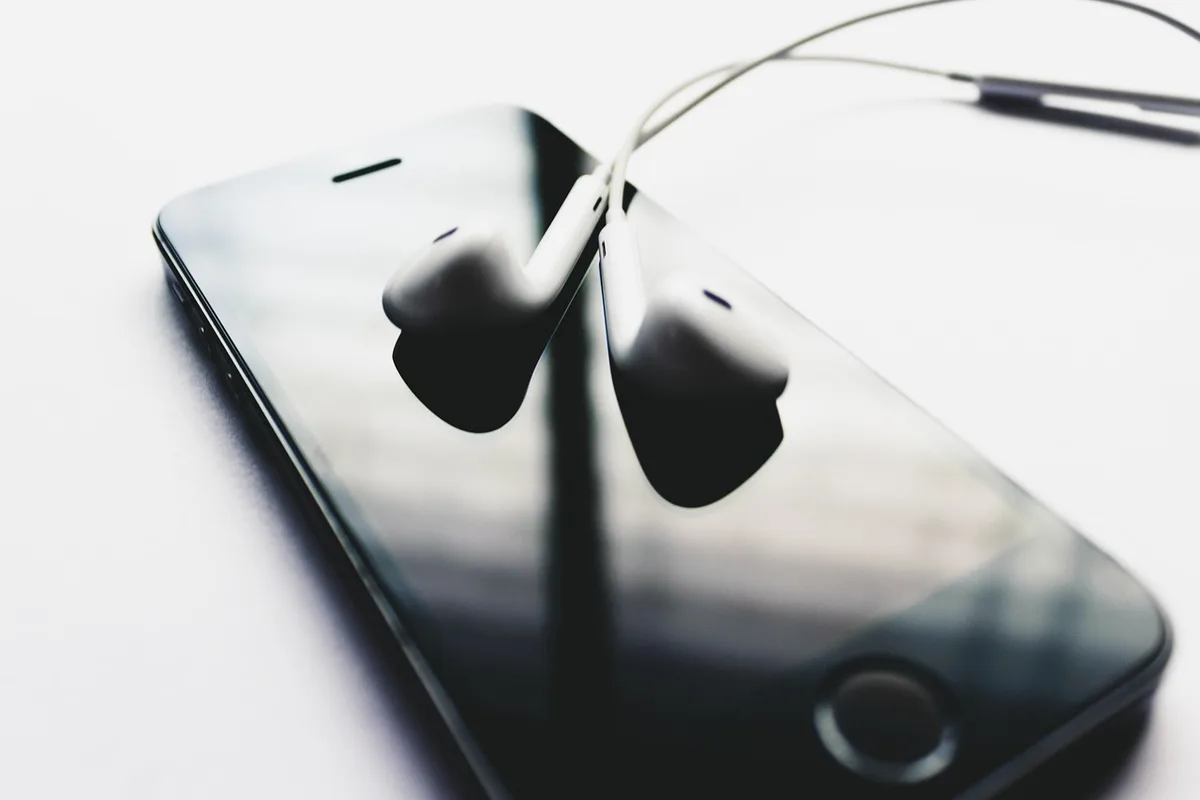 small open charging case and two earbuds on a café table, anonymous hands reaching for them