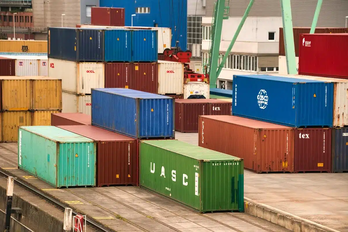 Trabajadores anónimos inspeccionan cajas en un muelle de carga con una tabla y papeles