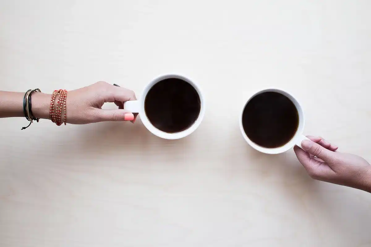 Manos anónimas sosteniendo gráficos económicos sobre una mesa de reunión con café