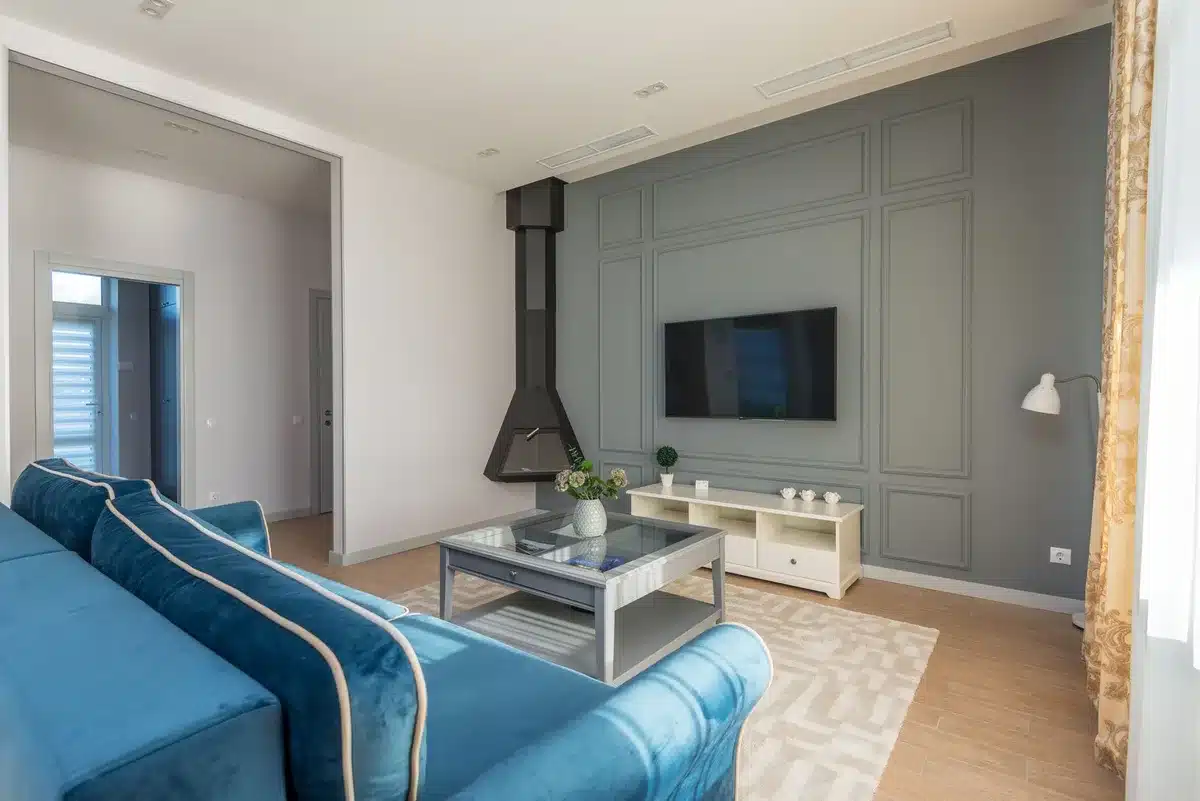 Empty living room with a large unbranded television screen glowing bright, deep blacks and vivid colors visible on screen