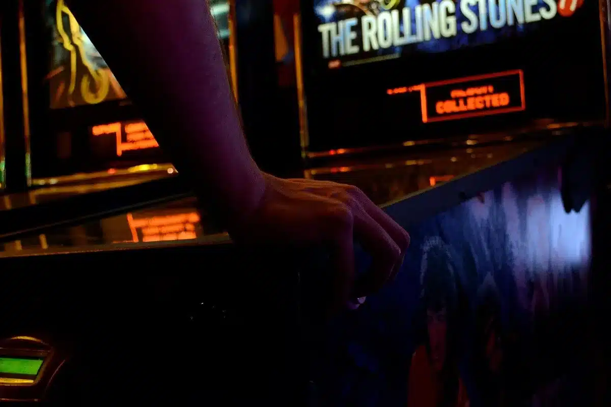 an empty arcade cabinet in a dimly lit room with horror-themed posters on the walls, no visible logos or people