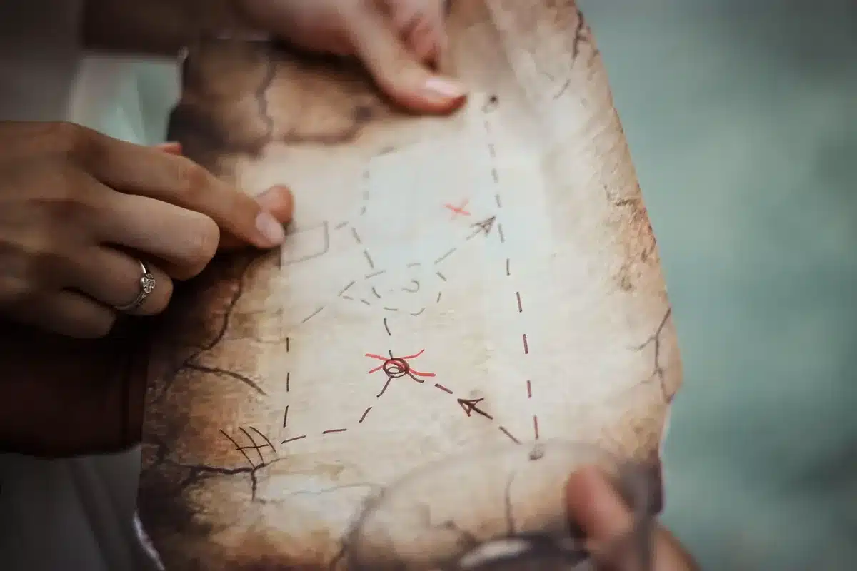 Manos y planos catastrales sobre mesa junto a pantalla con mapa digital