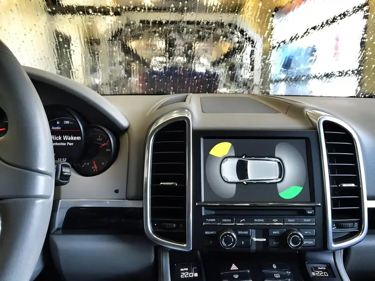 Interior view of a generic car dashboard showing a small digital instrument cluster and an 8-inch touchscreen, no brand visible, hands-free phone on wireless charger